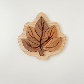 Completed wooden leaf puzzle with four walnut leaf pieces fitted into linden wood base. 