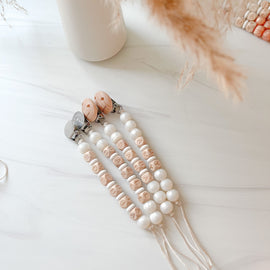 Metallic white personalized pacifier clip with silicone and name beads.