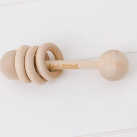 Baby teething on natural wooden rattle toy, safe antibacterial hardwood rattle for sensory development.