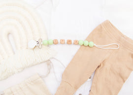 Baby-safe personalized pacifier clip in soft solid colors.