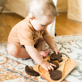 A child playing with a wooden vegetable puzzle made of natural linden wood, featuring pieces shaped like vegetables.